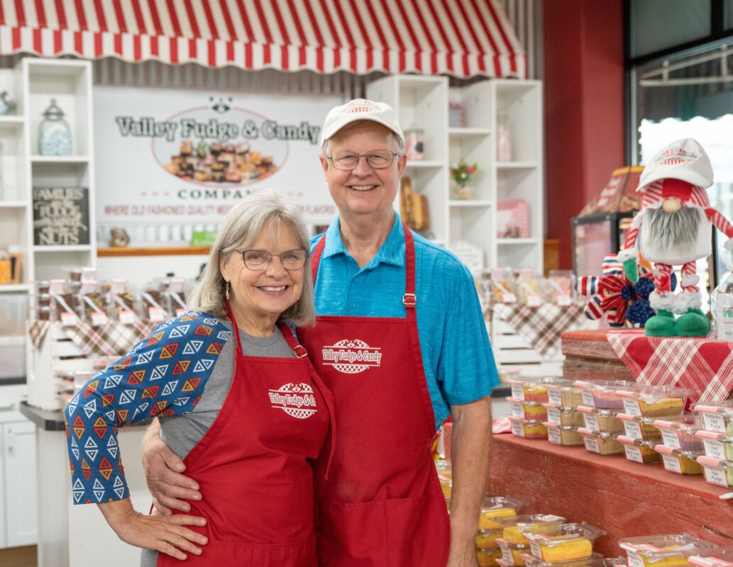 Linda and Steve Schulte standing in front of the register of Valley Fudge and Candy.