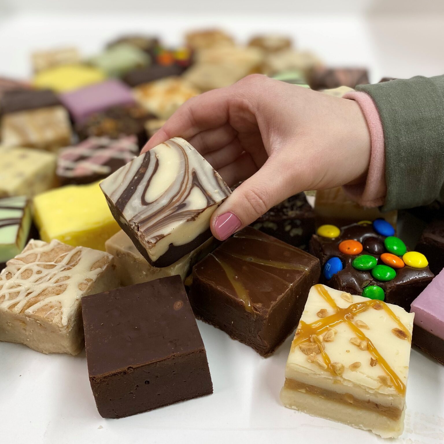 4 oz. piece of Cafe Mocha Fudge in hand with assorted fudge pieces in the background.