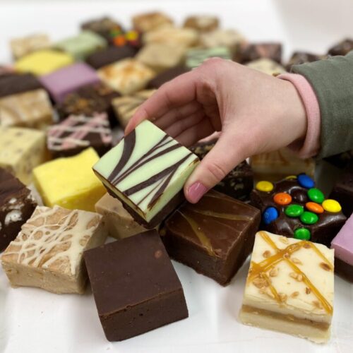4 oz. piece of Mint Chocolate Fudge in hand with assorted fudge pieces in the background.