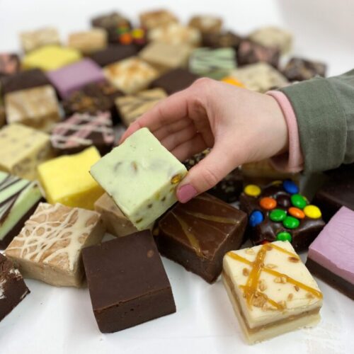 4 oz. piece of Pistachio Nut Fudge in Hand with assorted fudge pieces in the background.