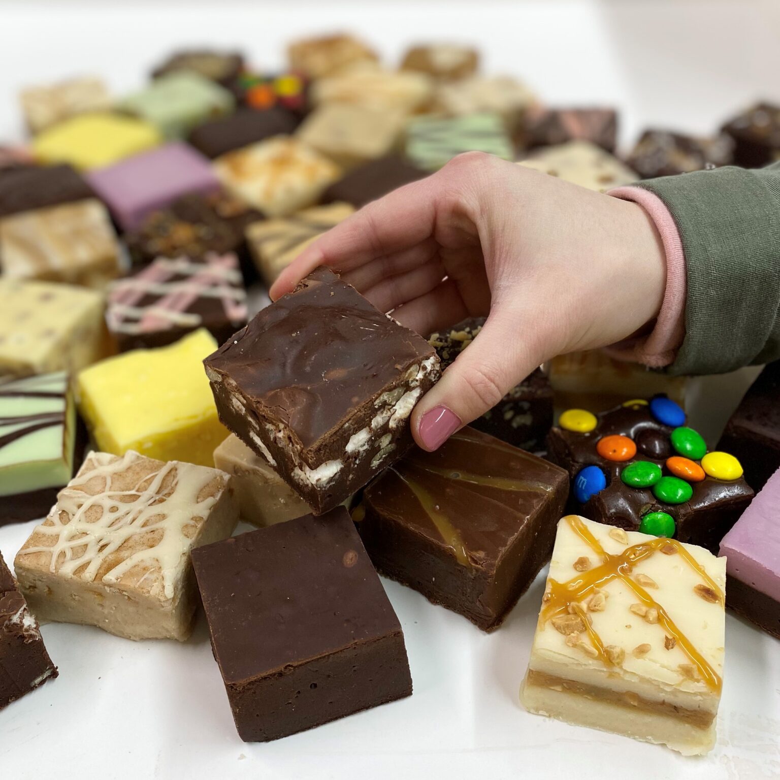 4 oz. piece of Rocky Road Fudge in Hand with assorted fudge pieces in the background.