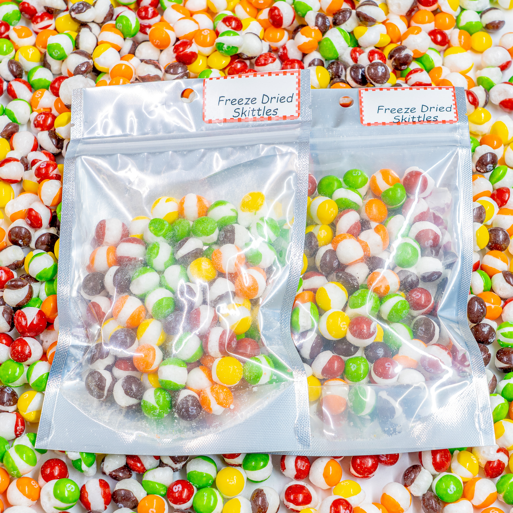 2 2.5 oz. bags of freeze dried skittles on top of an assortment of freeze dried skittles out of bag